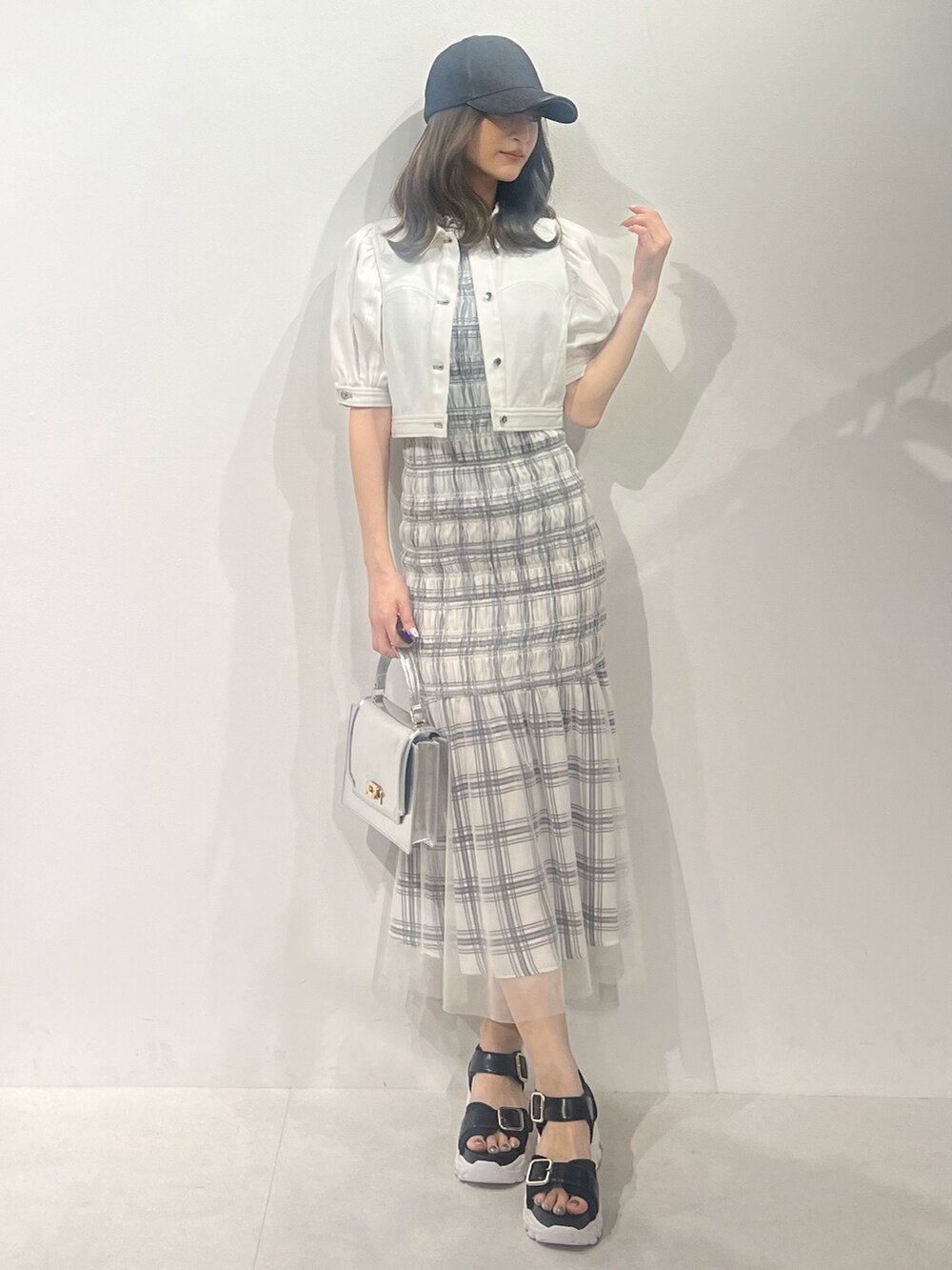 ブラック系のサンダル、ホワイト系のデニムジャケット、ホワイト系のワンピースを着用したレディースの春コーディネートの5枚目の写真