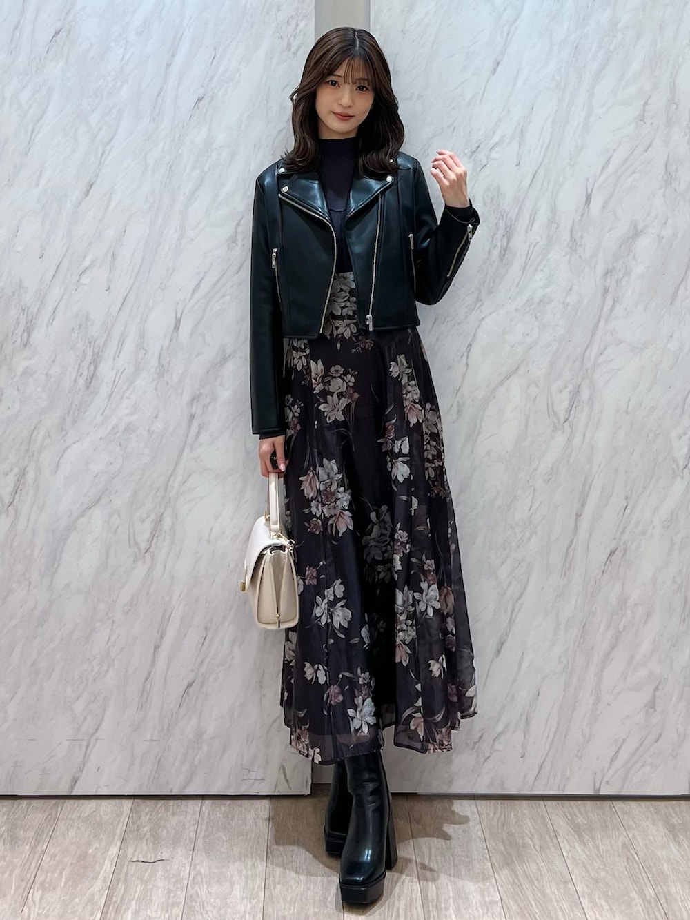 ブラック系のライダースジャケット、グレー系のワンピース、ホワイト系のハンドバッグを着用したレディースの冬コーディネートの2枚目の写真