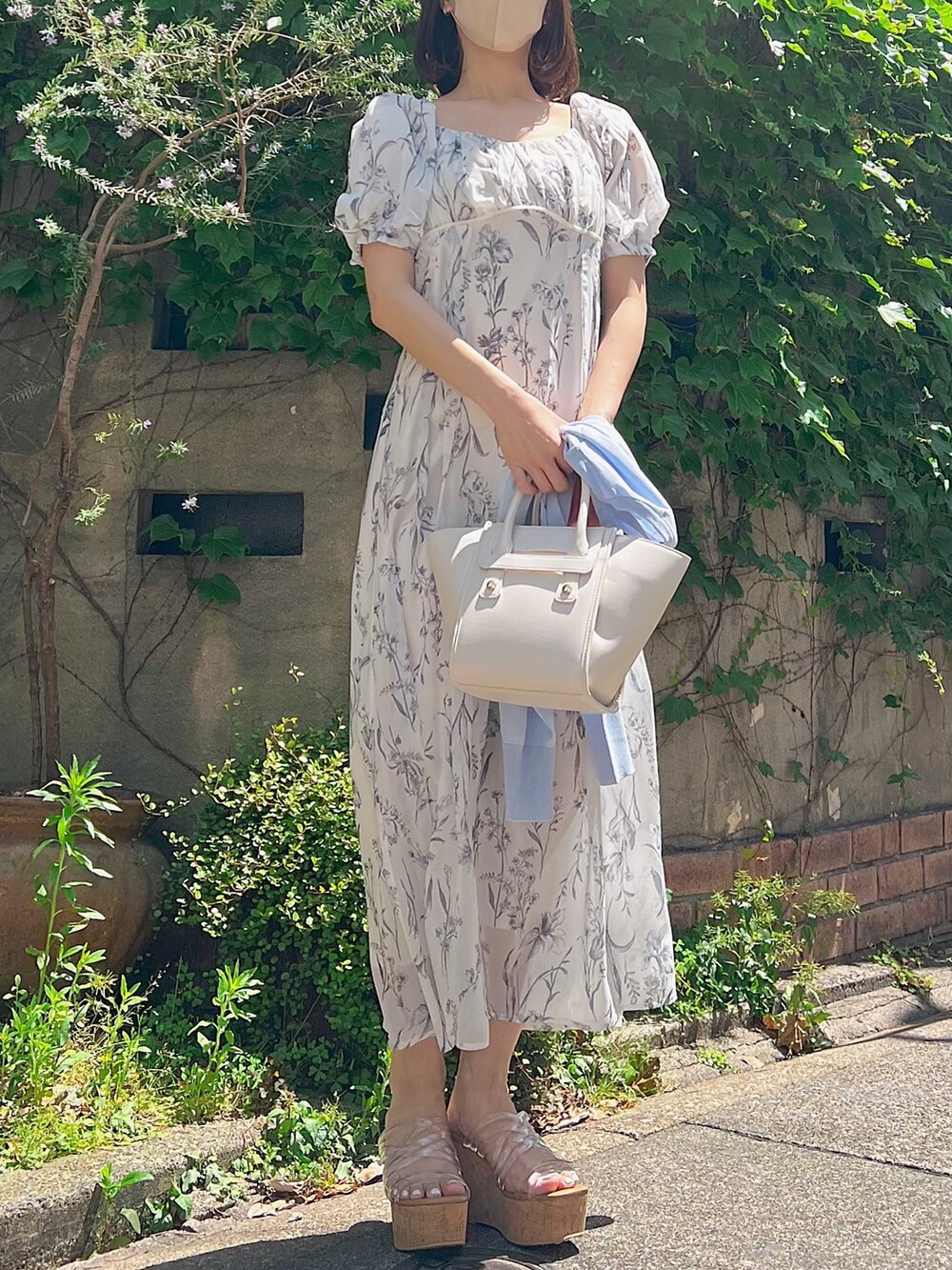 ホワイト系のワンピース、ブルー系のカーディガン/ボレロ、その他のサンダルを着用したレディースの春コーディネートの4枚目の写真