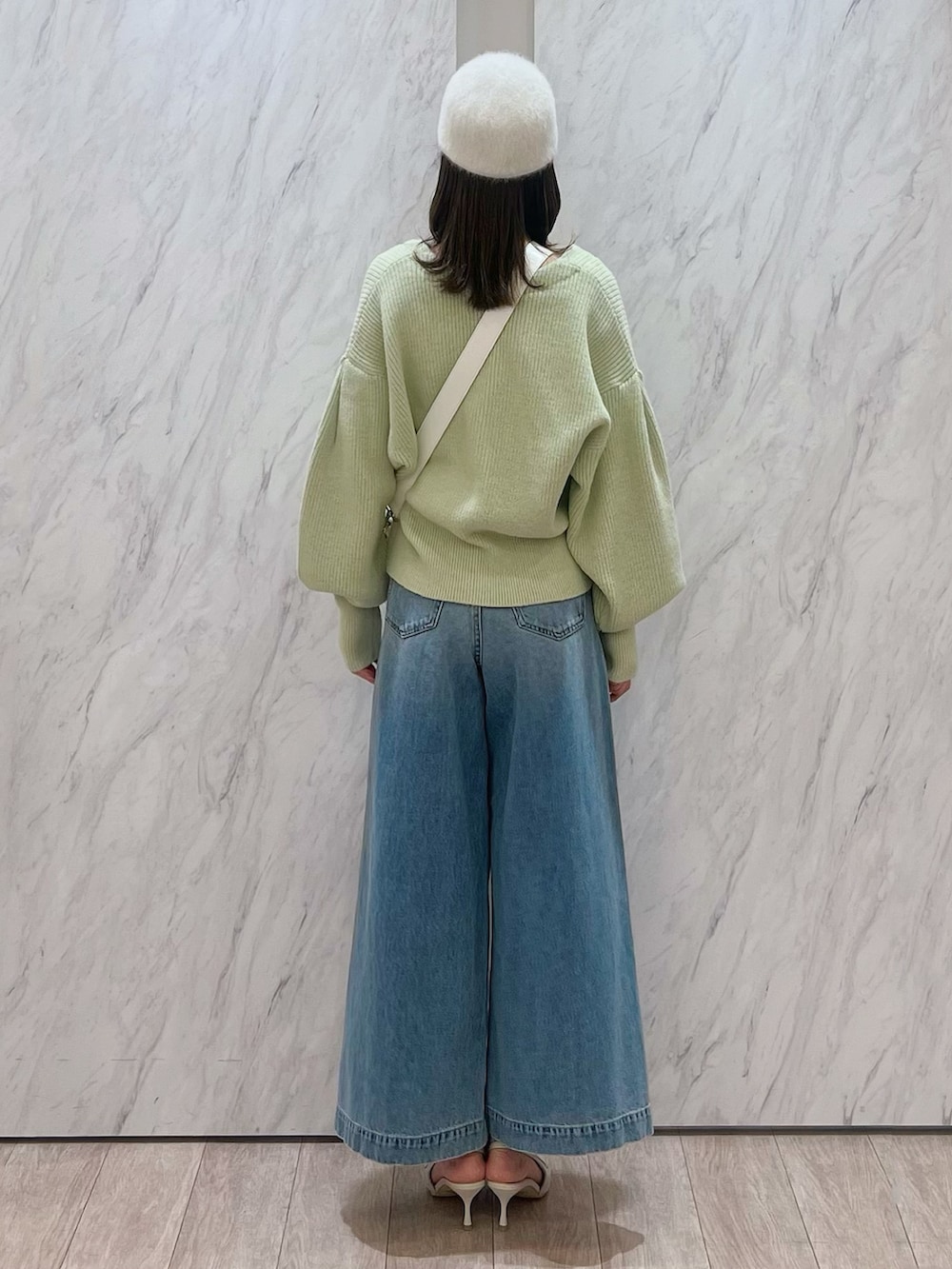 グリーン系のカーディガン/ボレロ、ホワイト系のショルダーバッグ、ブルー系のデニムパンツを着用したレディースの冬コーディネートの3枚目の写真