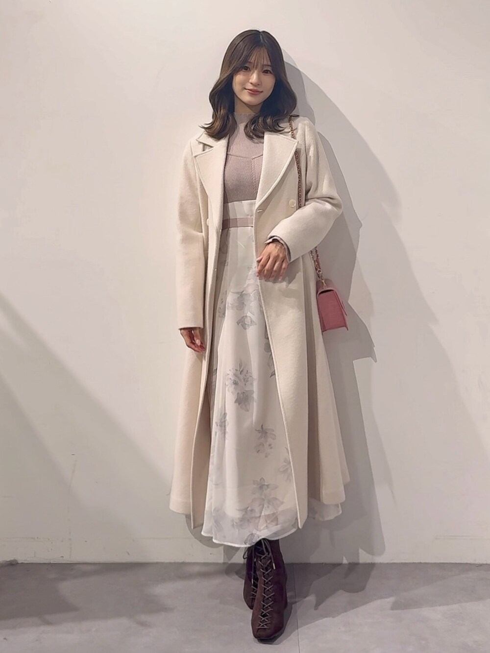 ホワイト系のその他アウター、ピンク系のハンドバッグ、ブラウン系のブーツを着用したレディースの秋コーディネートの2枚目の写真