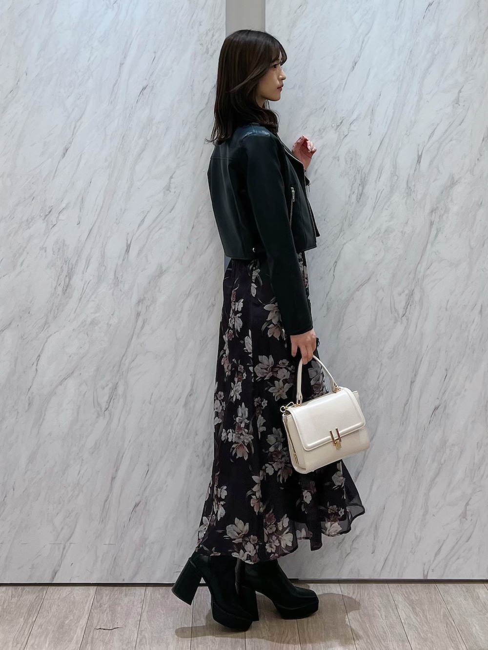 ブラック系のライダースジャケット、グレー系のワンピース、ホワイト系のハンドバッグを着用したレディースの冬コーディネートの3枚目の写真