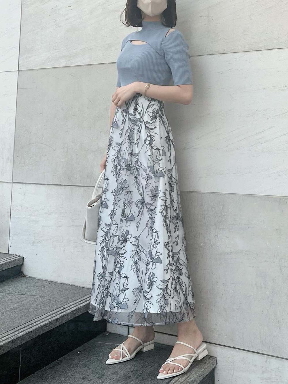 グレー系のスカート、ブルー系のニット/セーター、ホワイト系のトートバッグを着用したレディースの春コーディネートの2枚目の写真