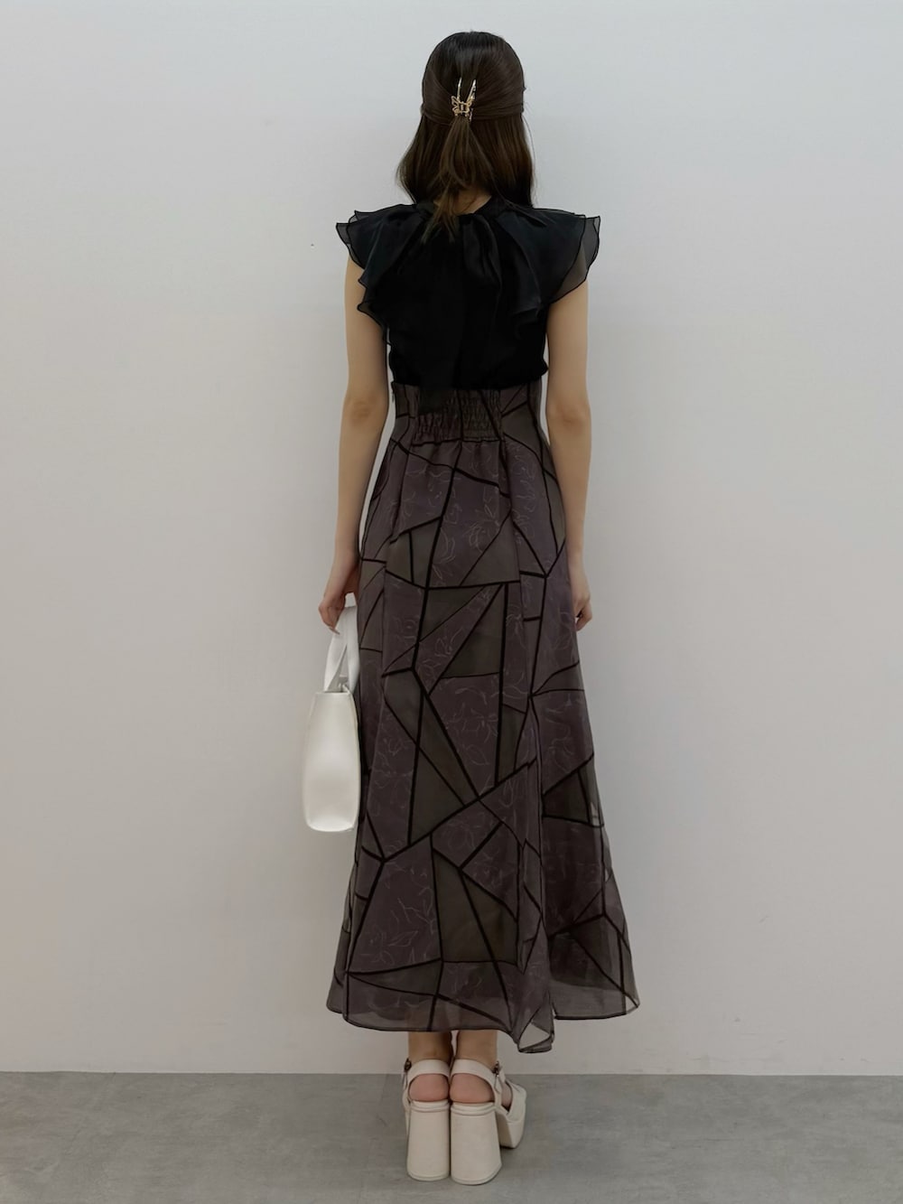 ブラック系のニット/セーター、ブラウン系のスカート、ホワイト系のトートバッグを着用したレディースの夏コーディネートの4枚目の写真