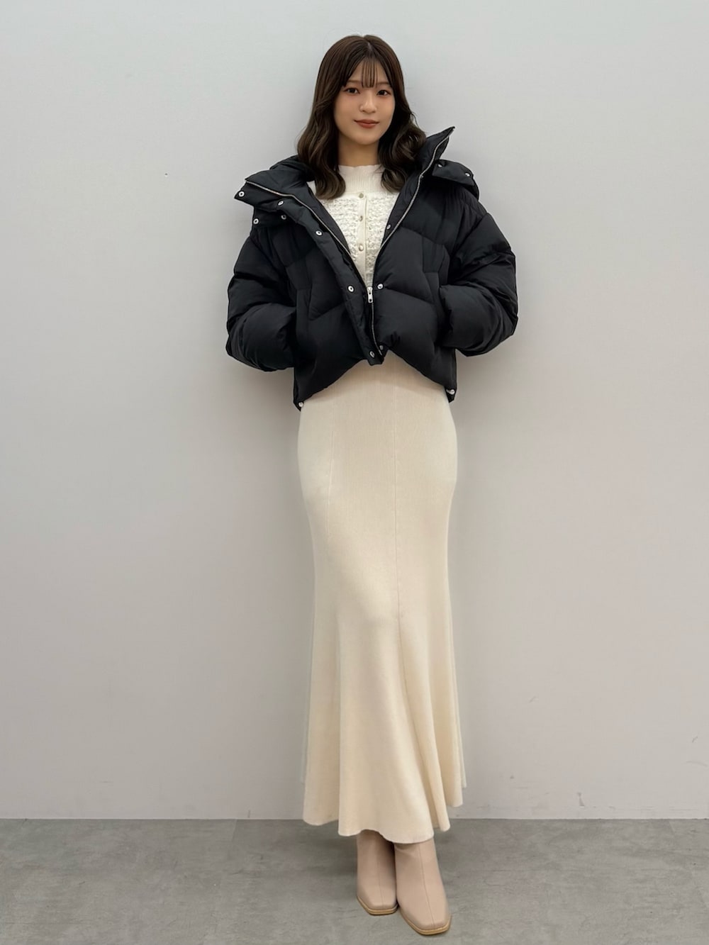 ブラック系のダウンジャケット/コート、ホワイト系のワンピース、ベージュ系のブーツを着用したレディースの秋コーディネートの5枚目の写真