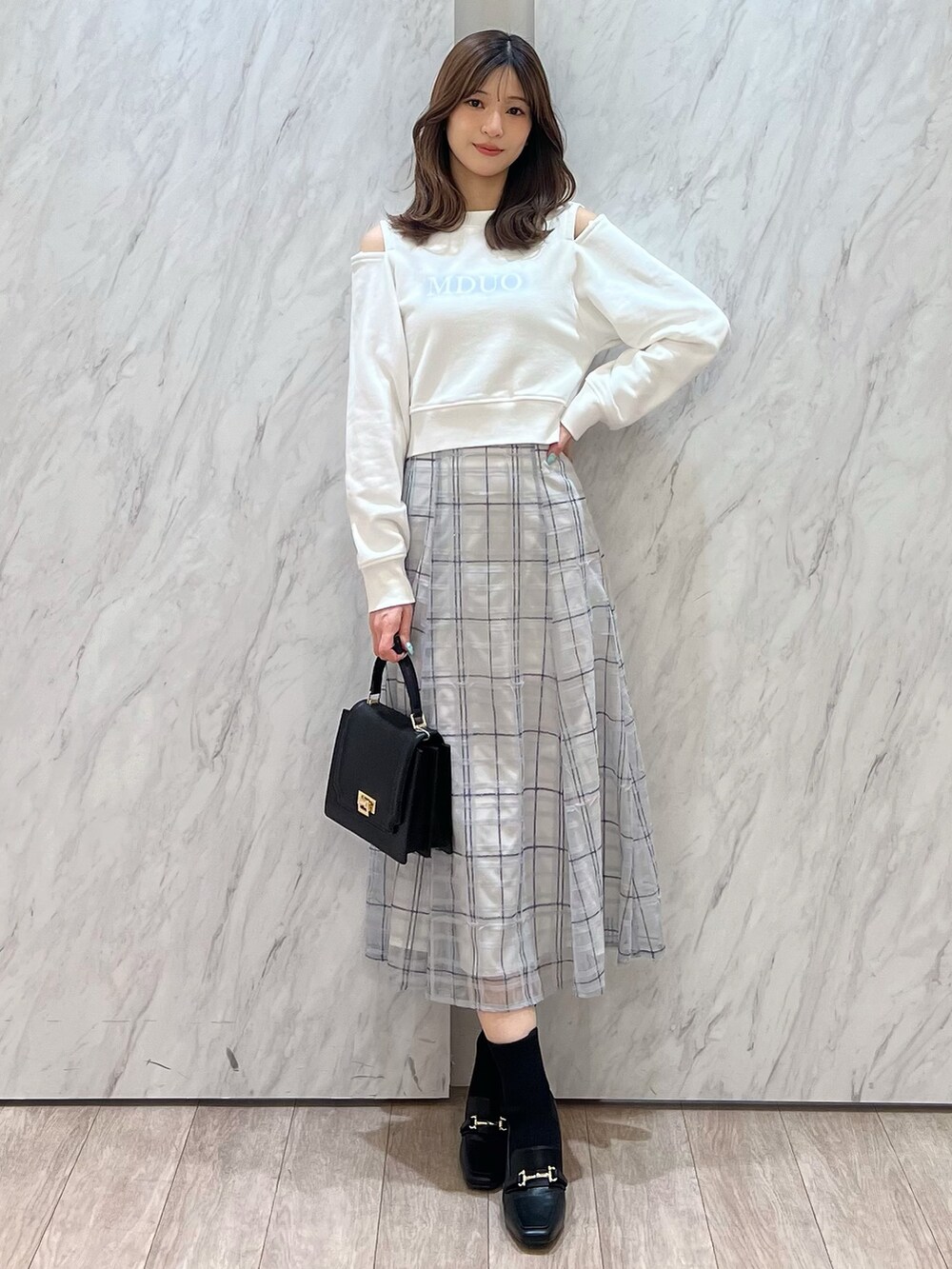 ホワイト系のTシャツ/カットソー、ブルー系のスカート、ブラック系のハンドバッグを着用したレディースの春コーディネートの5枚目の写真