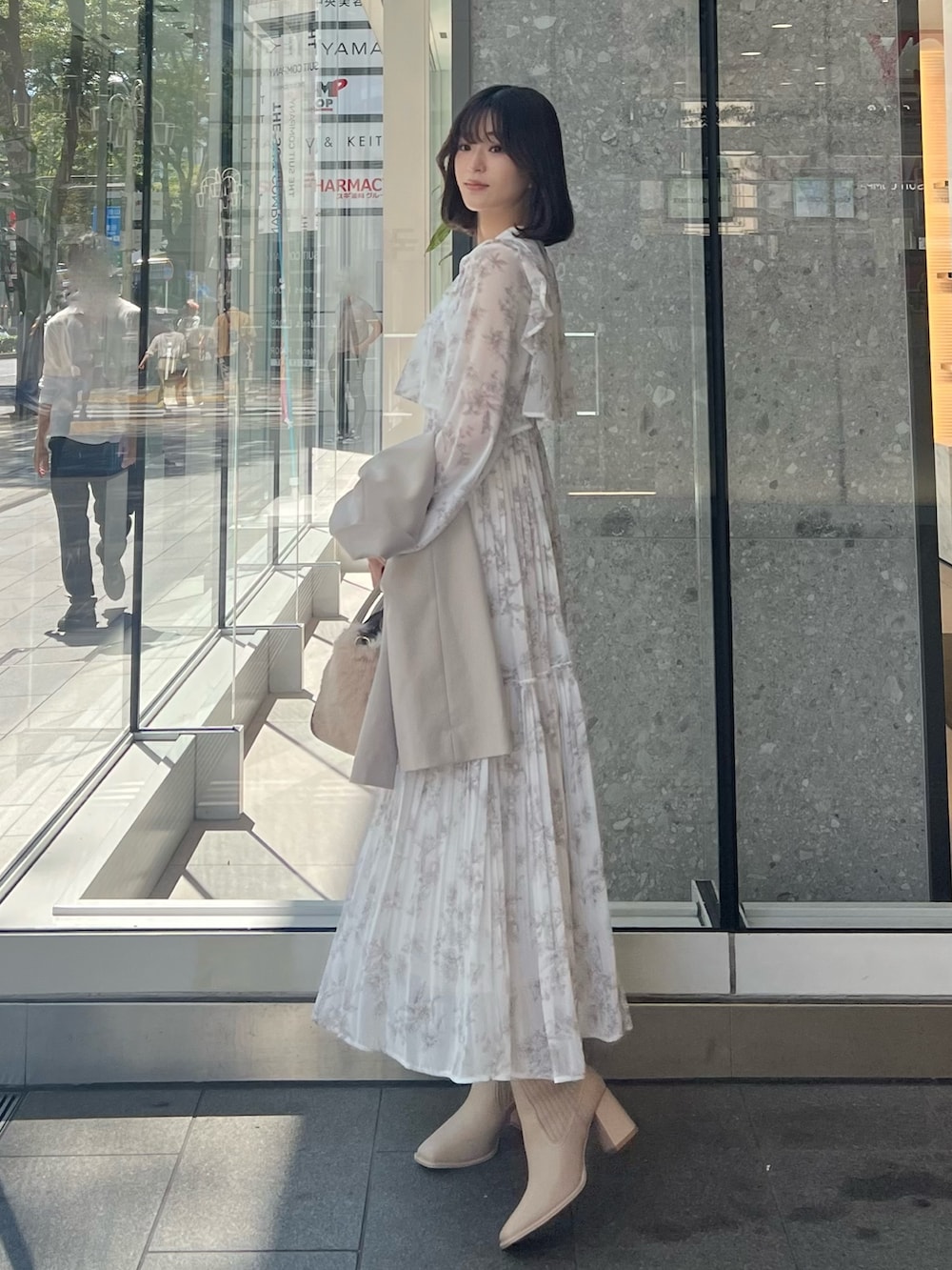 ホワイト系のハンドバッグ、ベージュ系のテーラードジャケット、ベージュ系のブーツを着用したレディースの秋コーディネートの6枚目の写真