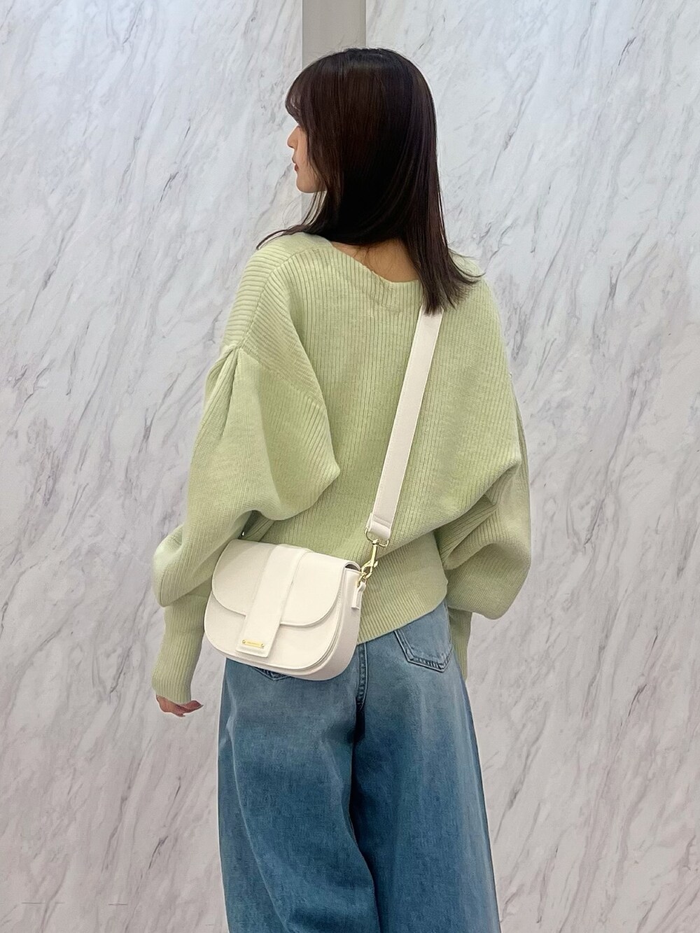 グリーン系のカーディガン/ボレロ、ホワイト系のショルダーバッグ、ブルー系のデニムパンツを着用したレディースの冬コーディネートの6枚目の写真