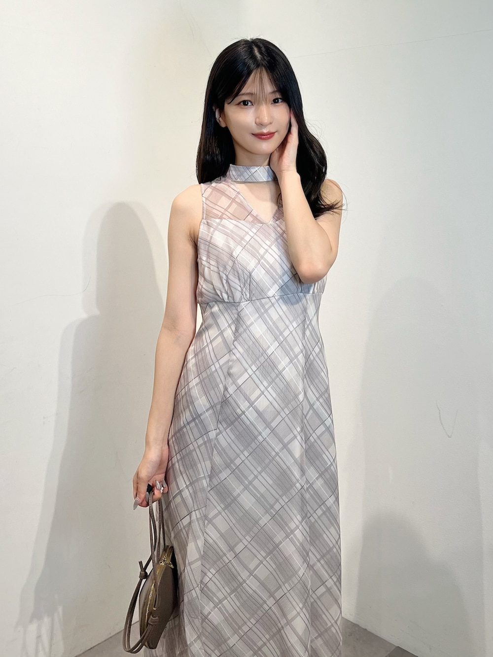 ベージュ系のワンピース、ブラウン系のサンダル、ベージュ系のショルダーバッグを着用したレディースの夏コーディネートの2枚目の写真