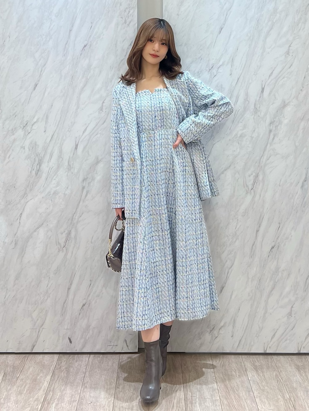 ブルー系のテーラードジャケット、ブルー系のワンピース、ブラウン系のハンドバッグを着用したレディースの冬コーディネートの5枚目の写真