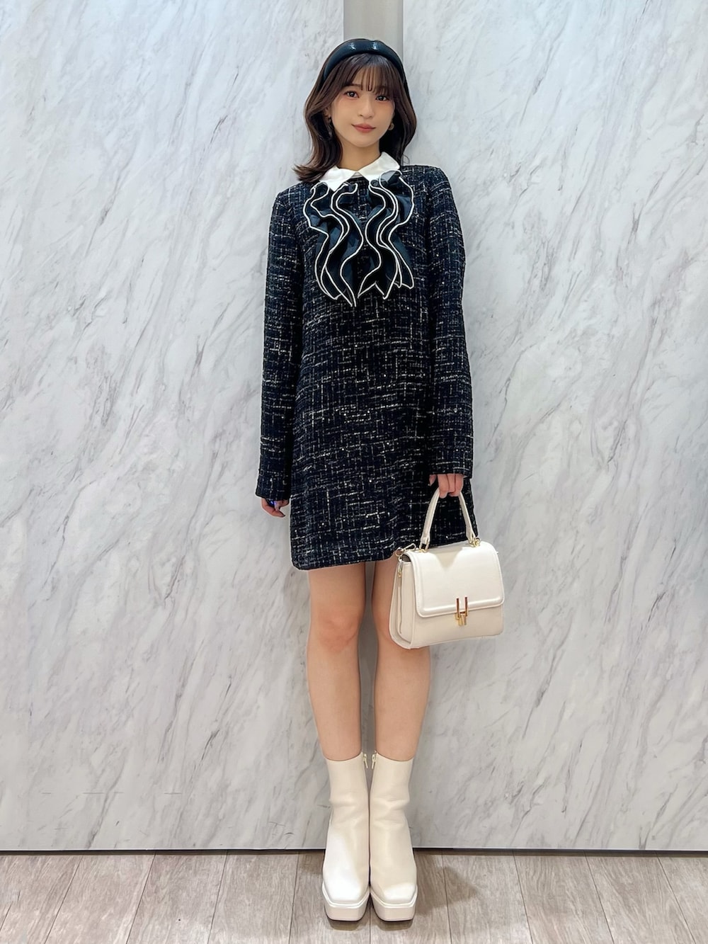 ホワイト系のブーツ、ホワイト系のハンドバッグ、ブラック系のワンピースを着用したレディースの秋コーディネートの2枚目の写真