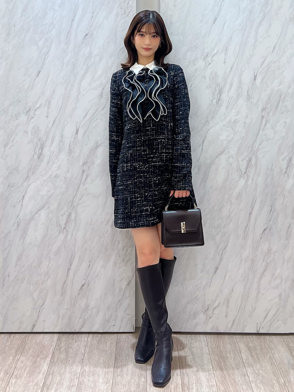 ブラック系のワンピース、ブラウン系のハンドバッグ、ブラウン系のブーツを着用したレディースの秋コーディネートの6枚目の写真