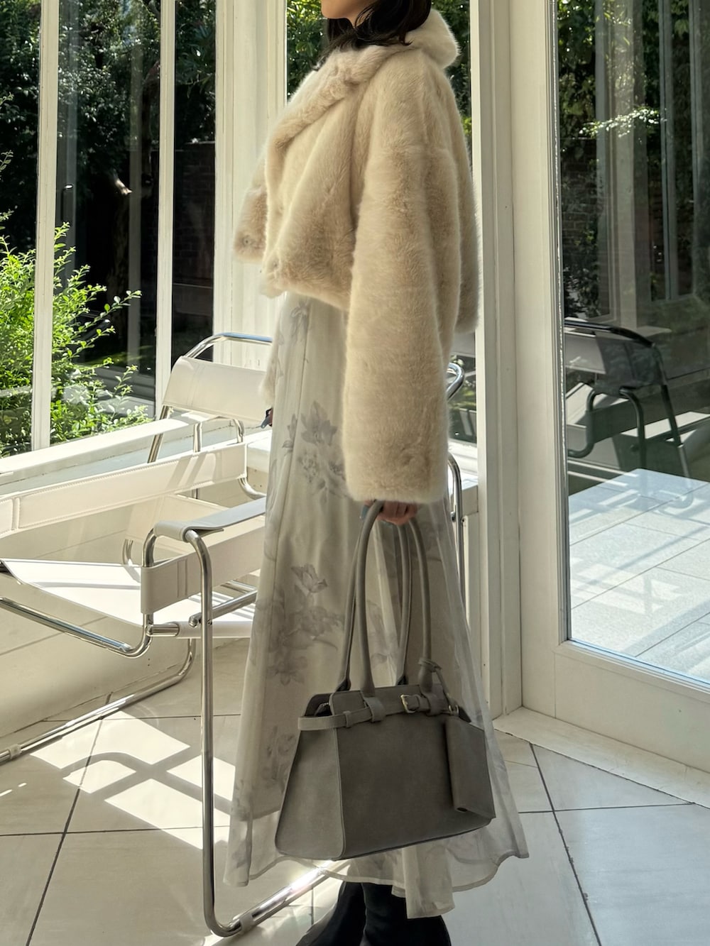 ベージュ系のワンピース、グレー系のハンドバッグ、ブラック系のブーツを着用したレディースの秋コーディネートの3枚目の写真