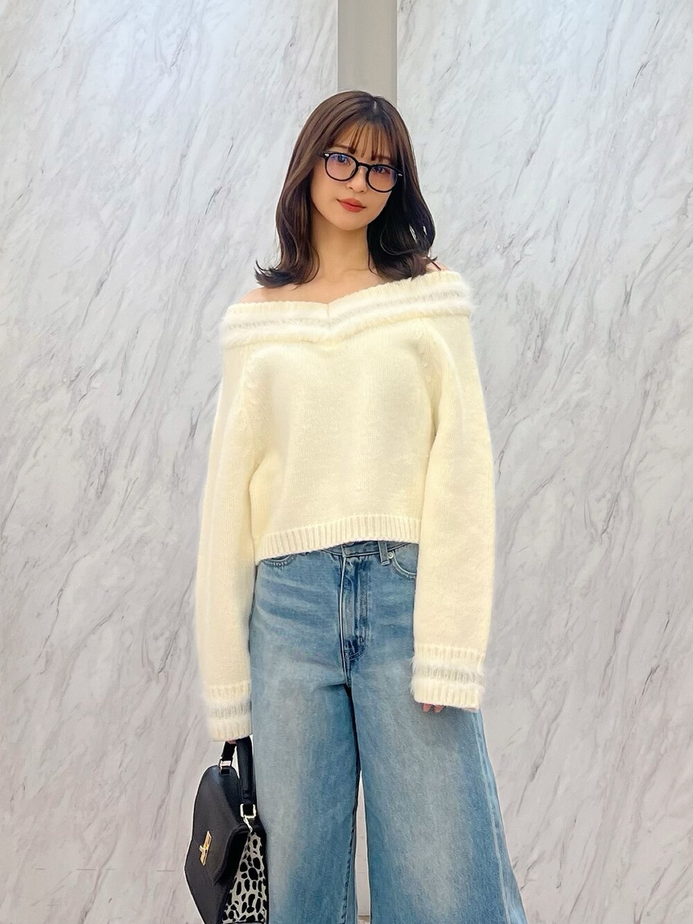ホワイト系のニット/セーター、ブルー系のデニムパンツ、ブラック系のハンドバッグを着用したレディースの冬コーディネートの2枚目の写真