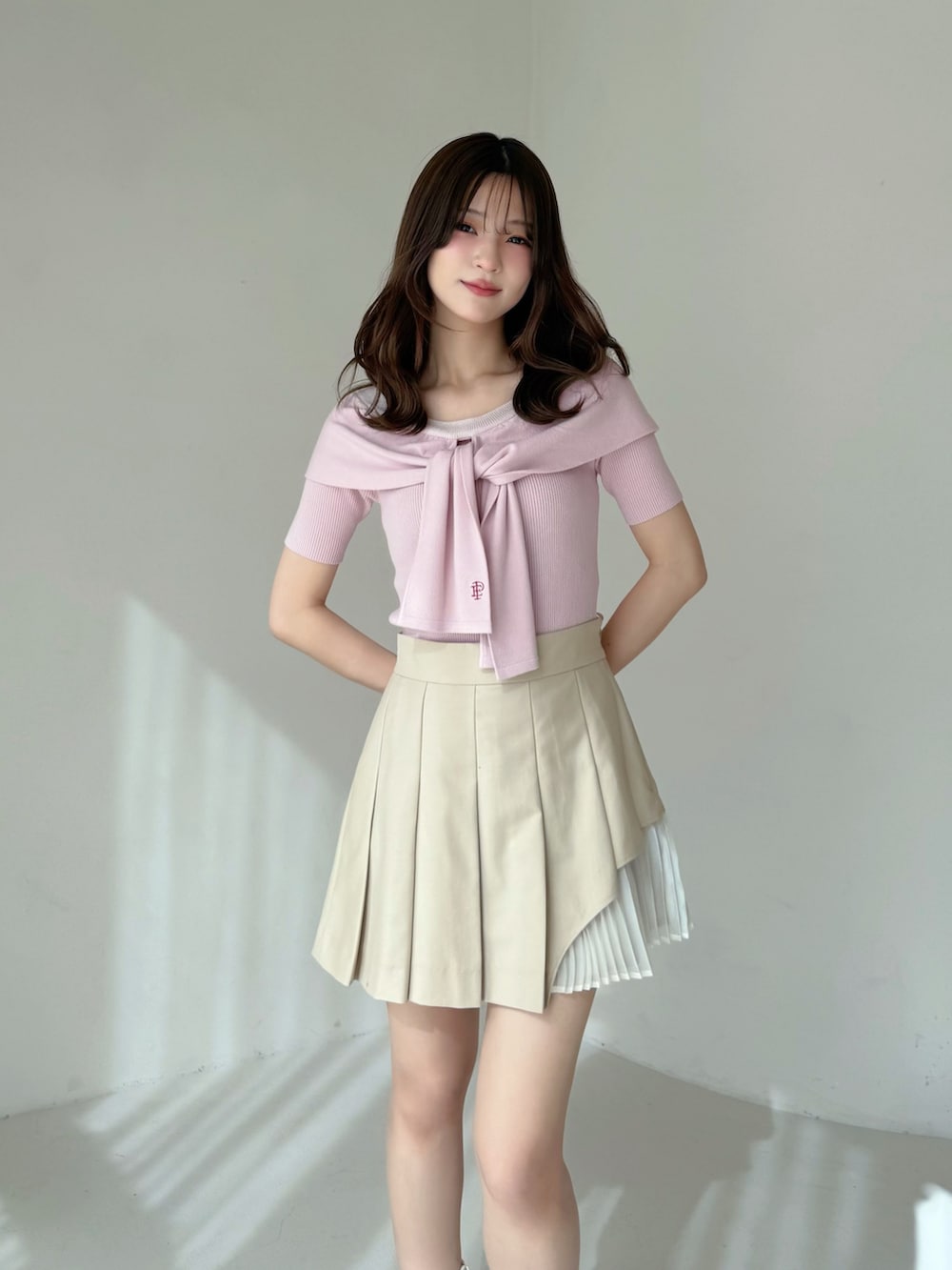 ベージュ系のスカート、ピンク系のニット/セーター、ホワイト系のブーツを着用したレディースの春コーディネートの2枚目の写真