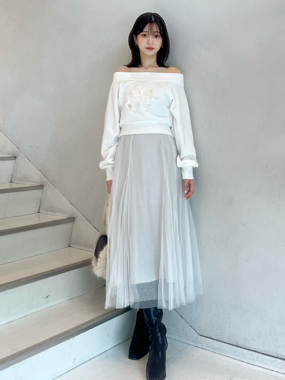 ブラウン系のショルダーバッグ、ホワイト系のスカート、ブラウン系のブーツを着用したレディースの秋コーディネートの5枚目の写真