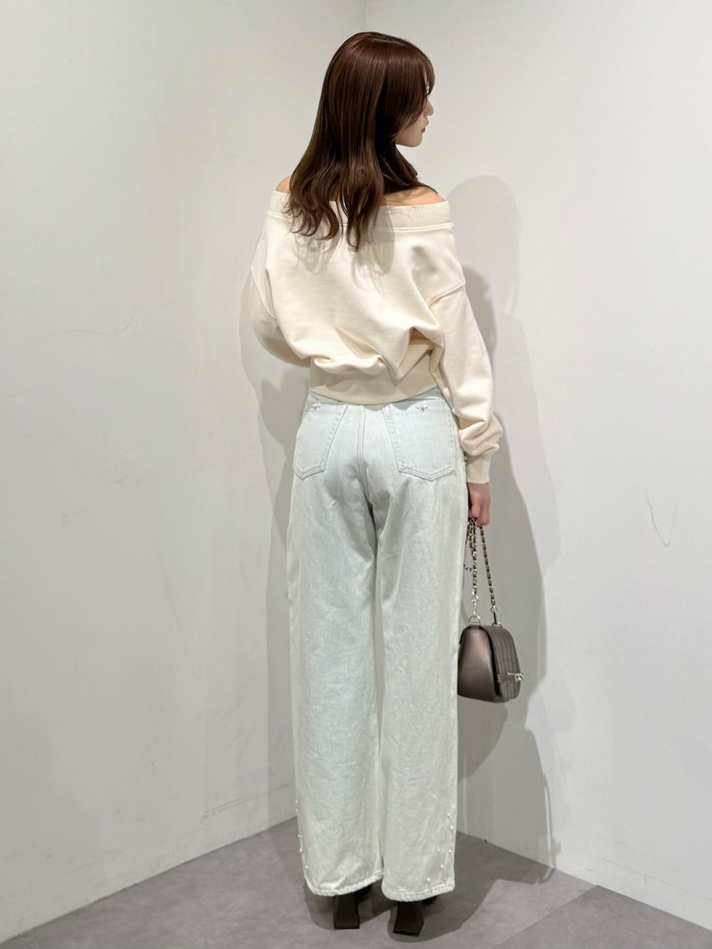 ブラウン系のパンプス、ブルー系のデニムパンツ、ブラウン系のハンドバッグを着用したレディースの春コーディネートの2枚目の写真