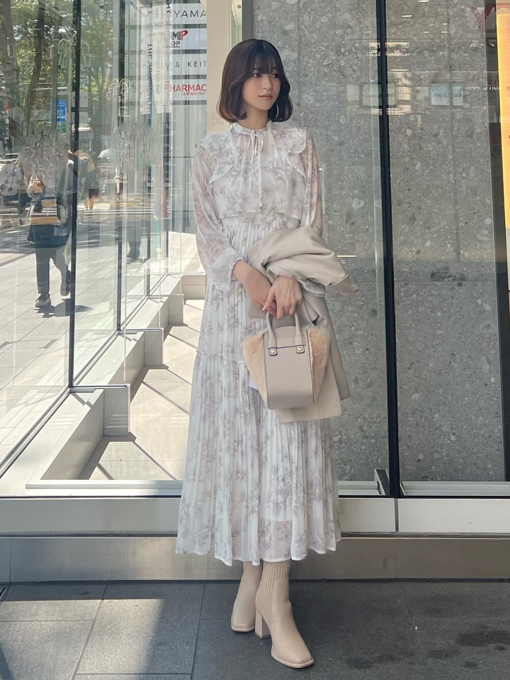 ホワイト系のハンドバッグ、ベージュ系のテーラードジャケット、ベージュ系のブーツを着用したレディースの秋コーディネートの5枚目の写真