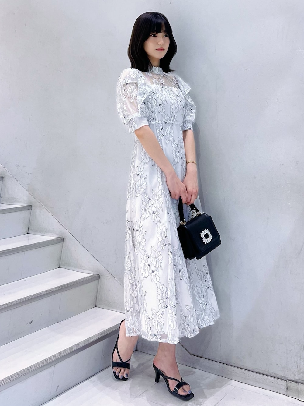 ブラック系のショルダーバッグ、ブラック系のサンダル、ホワイト系のワンピースを着用したレディースの夏コーディネートの4枚目の写真