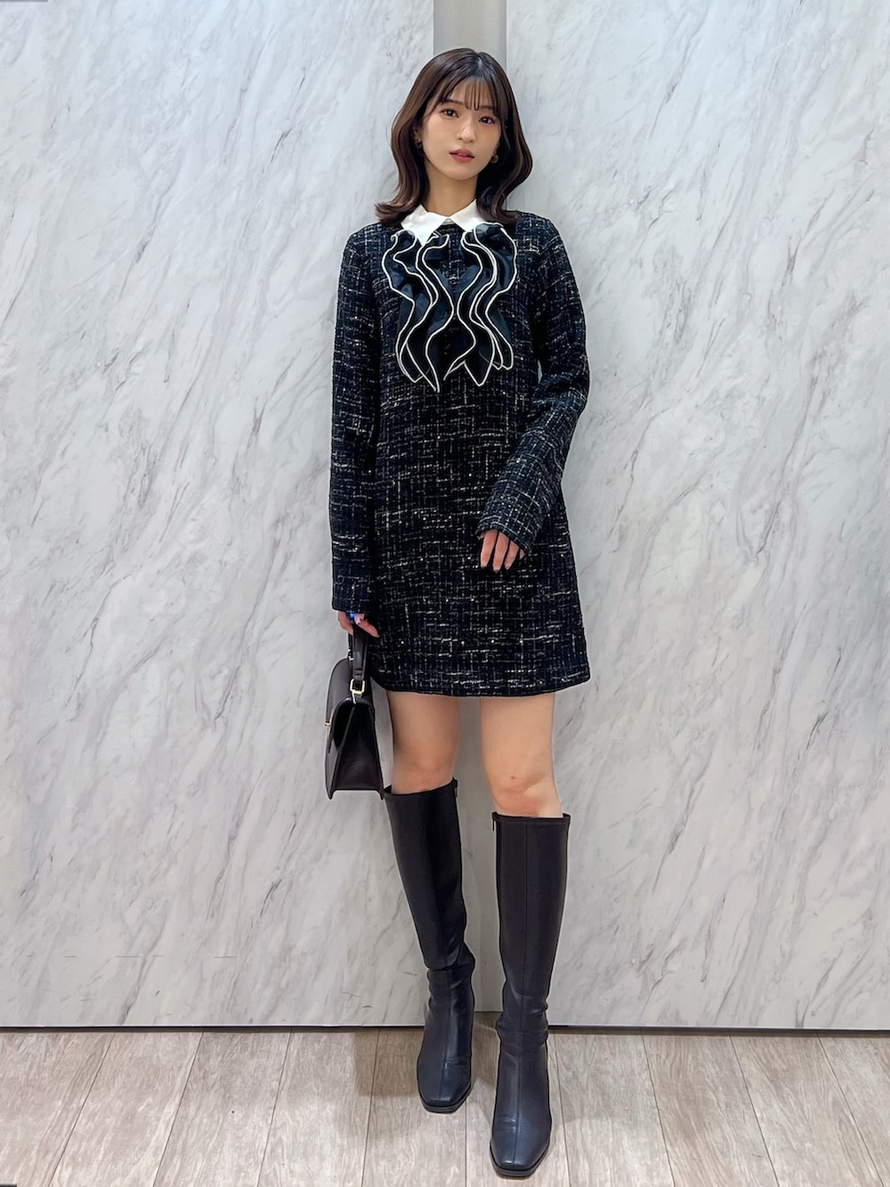 ブラック系のワンピース、ブラウン系のハンドバッグ、ブラウン系のブーツを着用したレディースの秋コーディネートの2枚目の写真