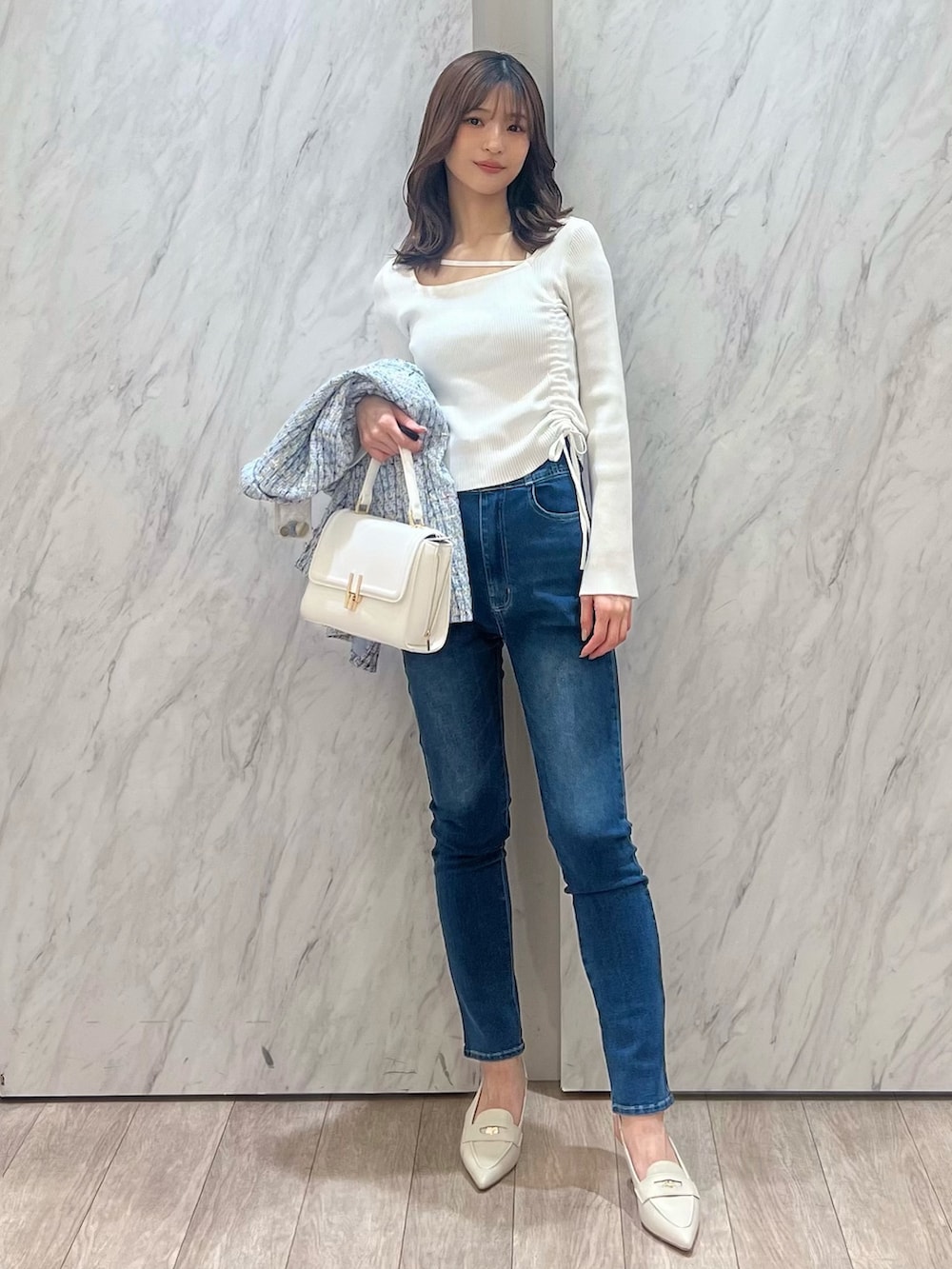 ブルー系のテーラードジャケット、ブルー系のデニムパンツ、ホワイト系のハンドバッグを着用したレディースの冬コーディネートの4枚目の写真