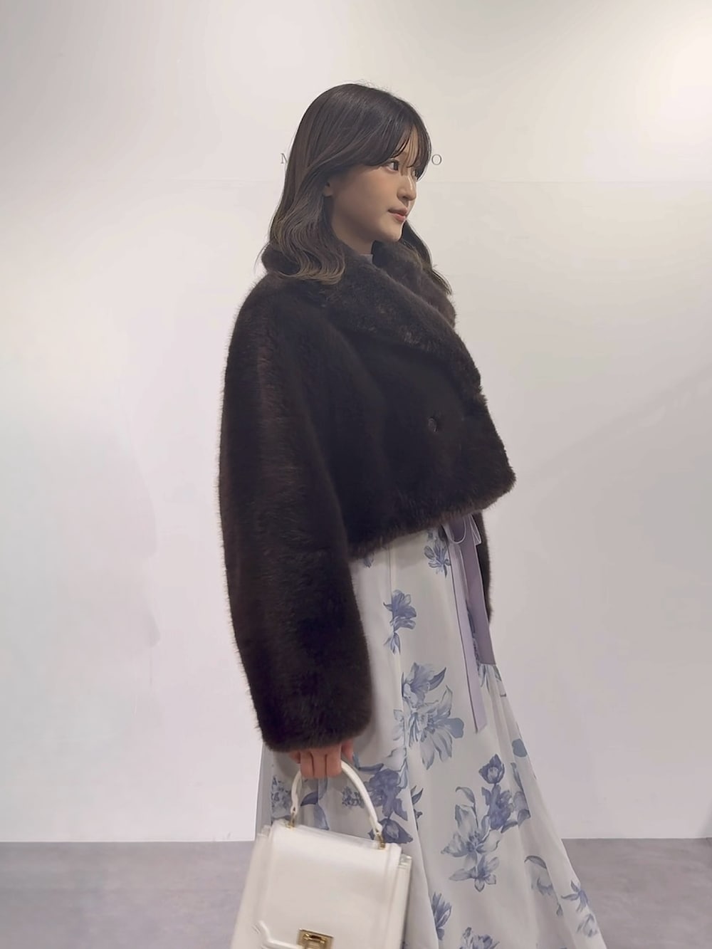 パープル系のワンピース、ブラウン系のブーツ、ホワイト系のハンドバッグを着用したレディースの秋コーディネートの3枚目の写真