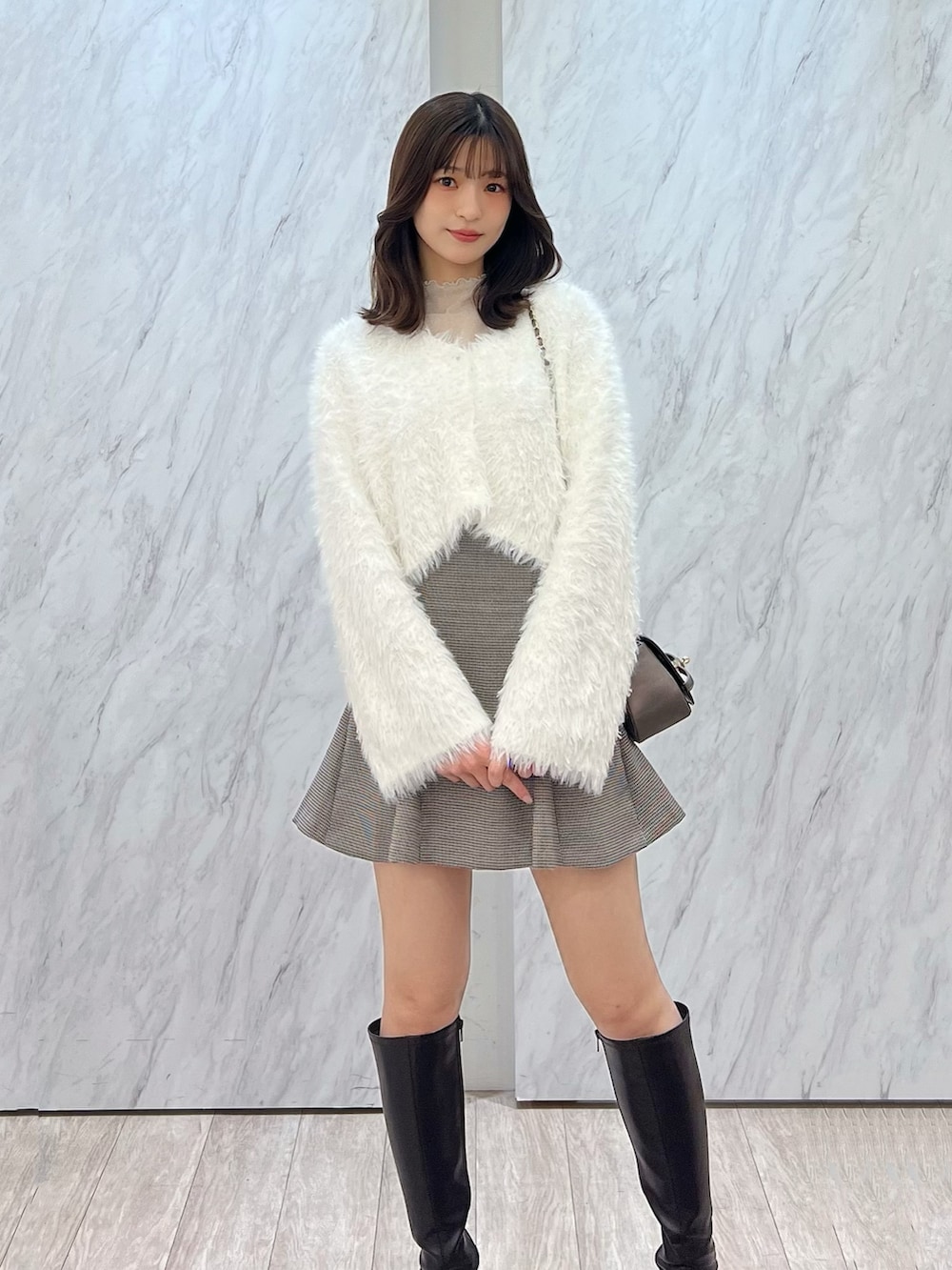 ホワイト系のカーディガン/ボレロ、ブラウン系のハンドバッグ、ゴールド系のTシャツ/カットソーを着用したレディースの冬コーディネートの5枚目の写真