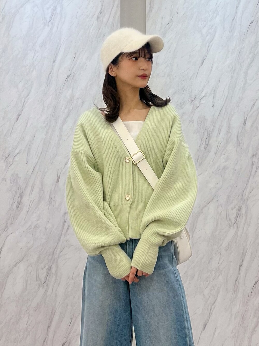 グリーン系のカーディガン/ボレロ、ホワイト系のショルダーバッグ、ブルー系のデニムパンツを着用したレディースの冬コーディネートの4枚目の写真