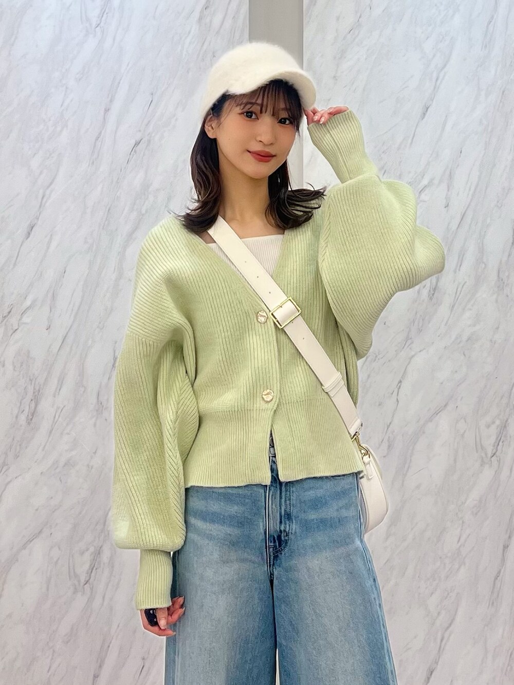 グリーン系のカーディガン/ボレロ、ホワイト系のショルダーバッグ、ブルー系のデニムパンツを着用したレディースの冬コーディネートの2枚目の写真