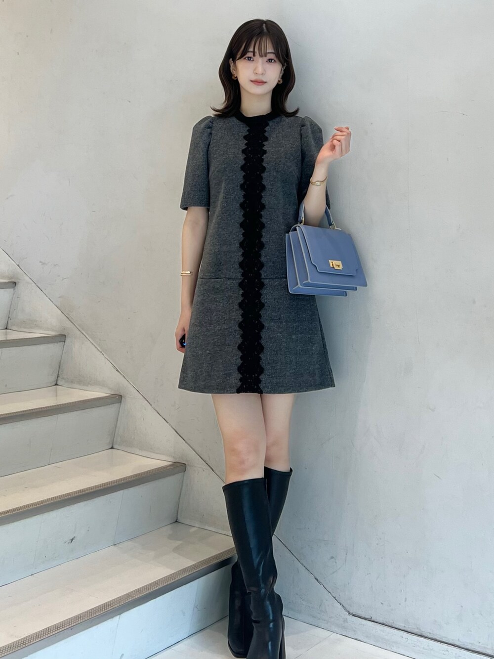 グレー系のワンピース、ブラック系のブーツ、ブルー系のハンドバッグを着用したレディースの秋コーディネートの6枚目の写真