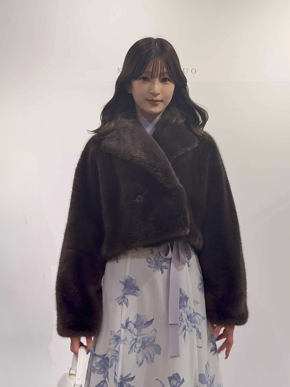 パープル系のワンピース、ブラウン系のブーツ、ホワイト系のハンドバッグを着用したレディースの秋コーディネートの6枚目の写真