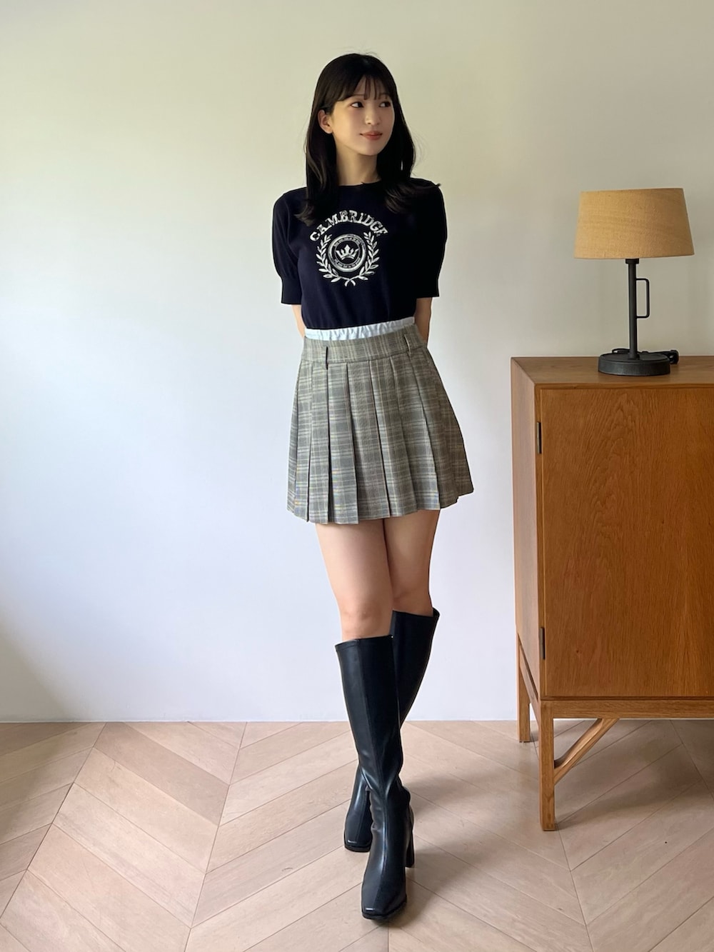 ブルー系のニット/セーター、グレー系のスカート、ブラック系のブーツを着用したレディースの夏コーディネートの6枚目の写真