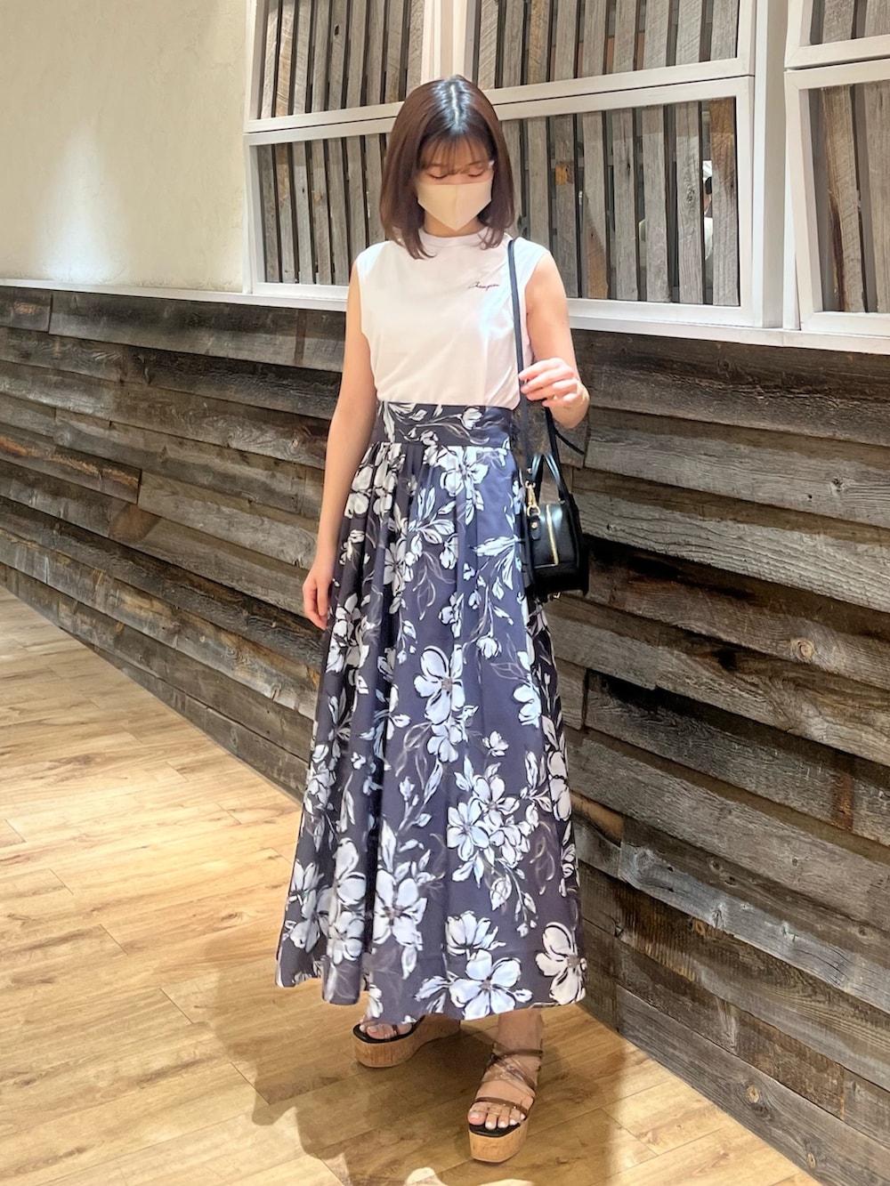 パープル系のスカート、ブラック系のハンドバッグ、ブラック系のサンダルを着用したレディースの春コーディネートの4枚目の写真