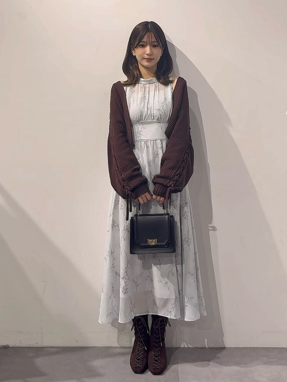 グリーン系のワンピース、ブラウン系のカーディガン/ボレロ、ブラック系のハンドバッグを着用したレディースの秋コーディネートの2枚目の写真