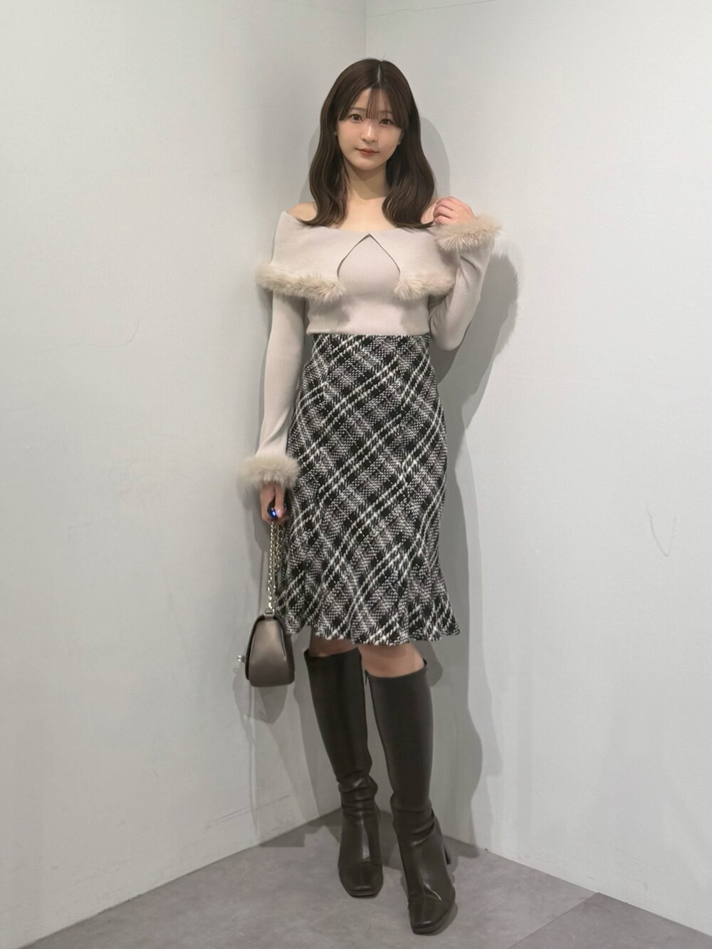 ベージュ系のニット/セーター、ブラック系のスカート、ブラウン系のブーツを着用したレディースの冬コーディネートの2枚目の写真