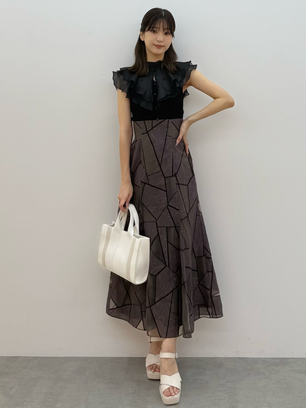 ブラック系のニット/セーター、ブラウン系のスカート、ホワイト系のトートバッグを着用したレディースの夏コーディネートの6枚目の写真