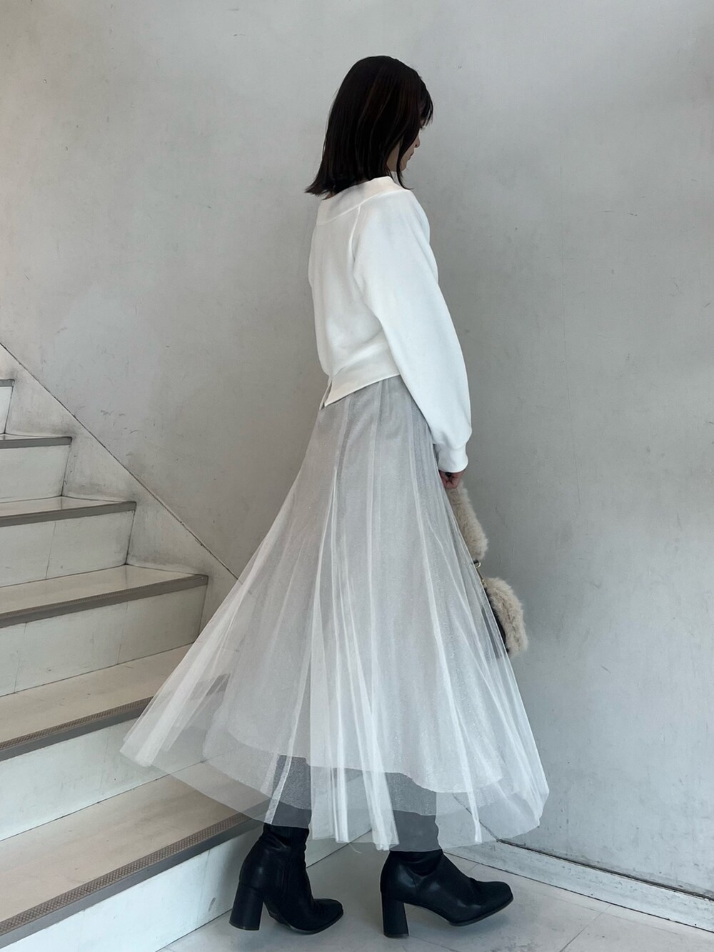 ブラウン系のショルダーバッグ、ホワイト系のスカート、ブラウン系のブーツを着用したレディースの秋コーディネートの8枚目の写真