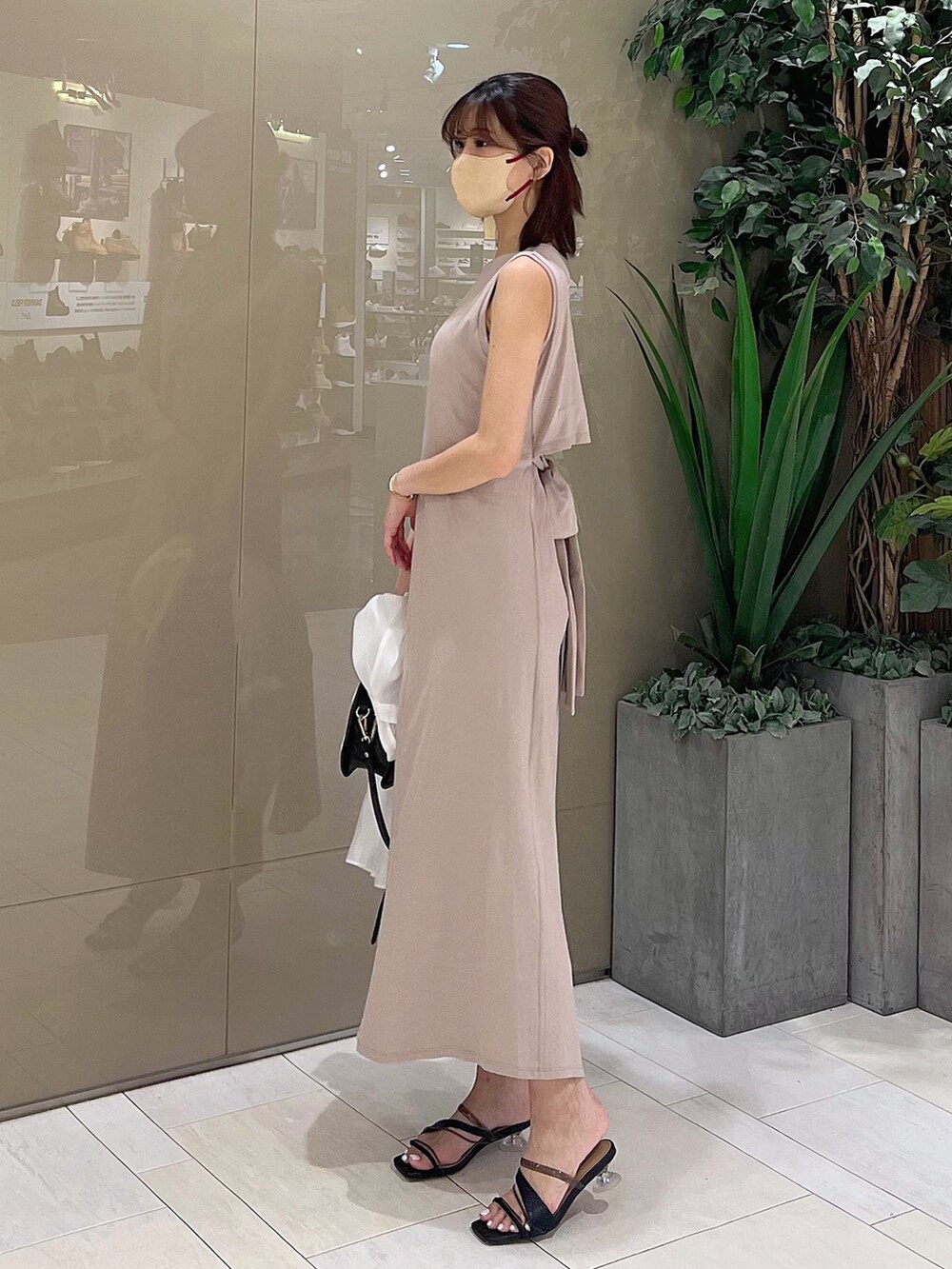 ベージュ系のワンピース、ブラック系のハンドバッグ、ブラック系のサンダルを着用したレディースの春コーディネートの7枚目の写真