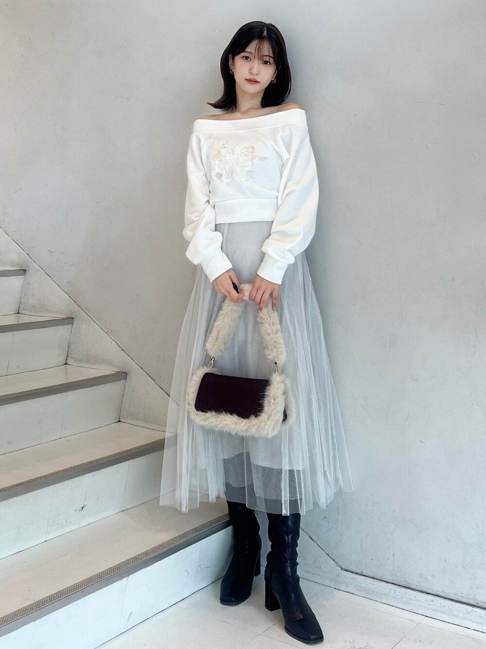 ブラウン系のショルダーバッグ、ホワイト系のスカート、ブラウン系のブーツを着用したレディースの秋コーディネートの7枚目の写真