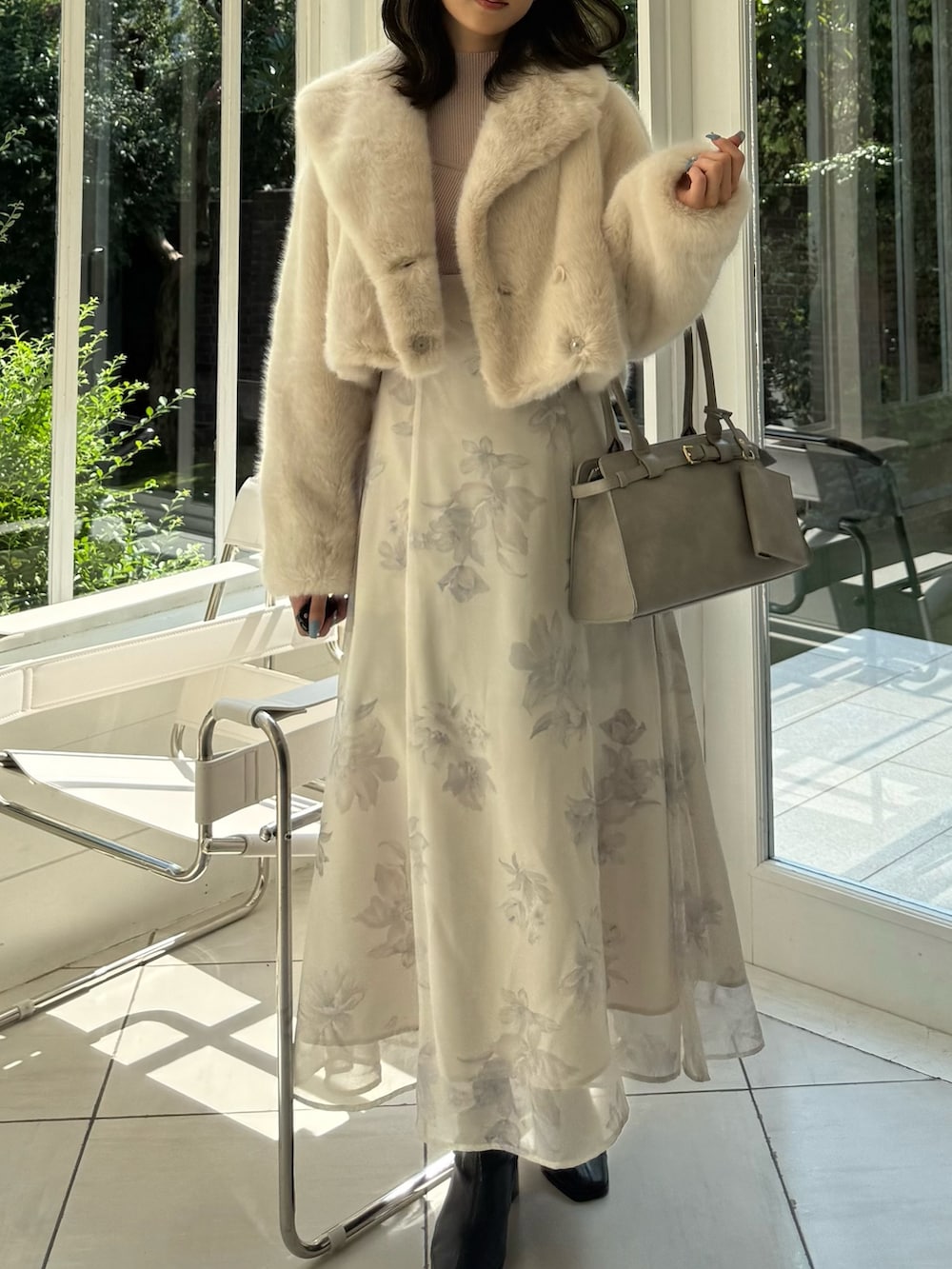 ベージュ系のワンピース、グレー系のハンドバッグ、ブラック系のブーツを着用したレディースの秋コーディネートの2枚目の写真