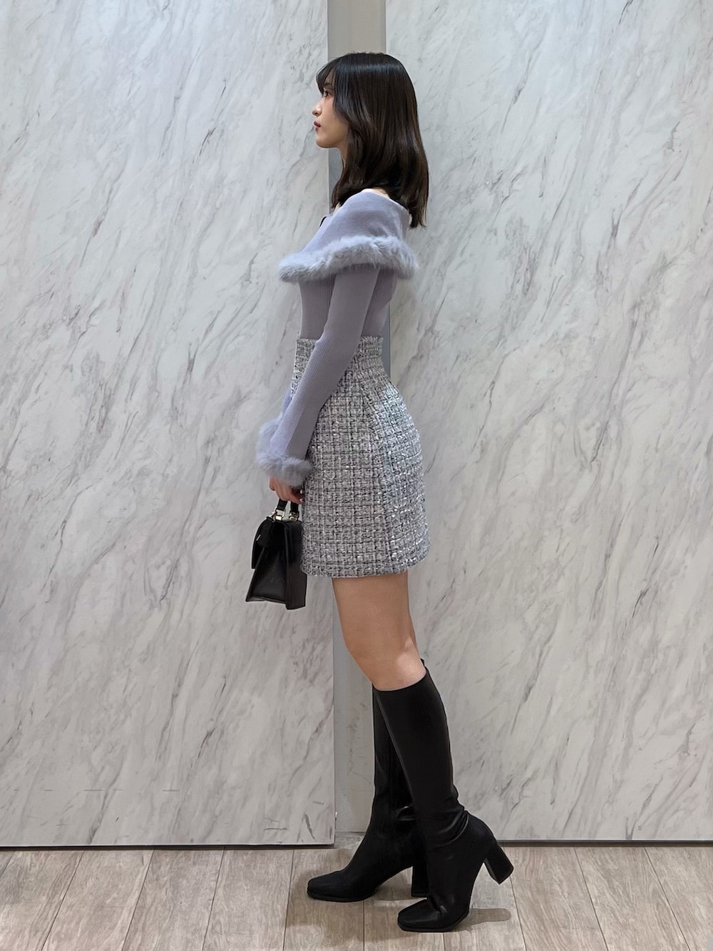 ブラウン系のブーツ、ブラウン系のハンドバッグ、ホワイト系のスカートを着用したレディースの冬コーディネートの3枚目の写真