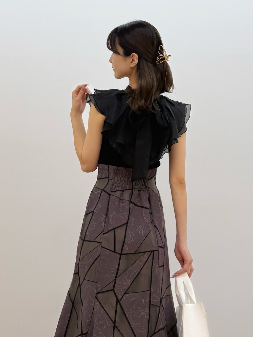 ブラック系のニット/セーター、ブラウン系のスカート、ホワイト系のトートバッグを着用したレディースの夏コーディネートの5枚目の写真