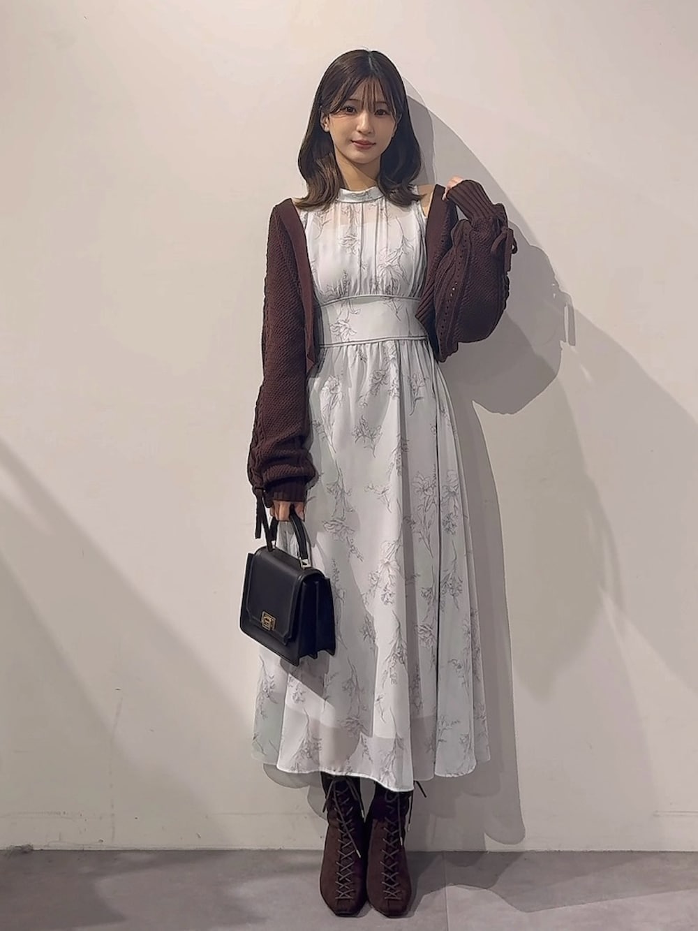グリーン系のワンピース、ブラウン系のカーディガン/ボレロ、ブラック系のハンドバッグを着用したレディースの秋コーディネートの8枚目の写真
