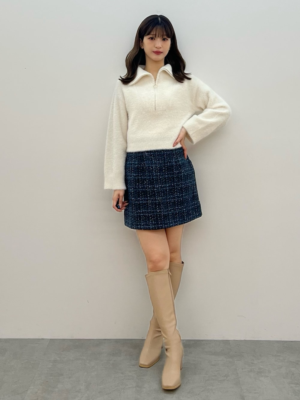 ホワイト系のニット/セーター、ブラック系のスカート、ベージュ系のブーツを着用したレディースの秋コーディネートの10枚目の写真