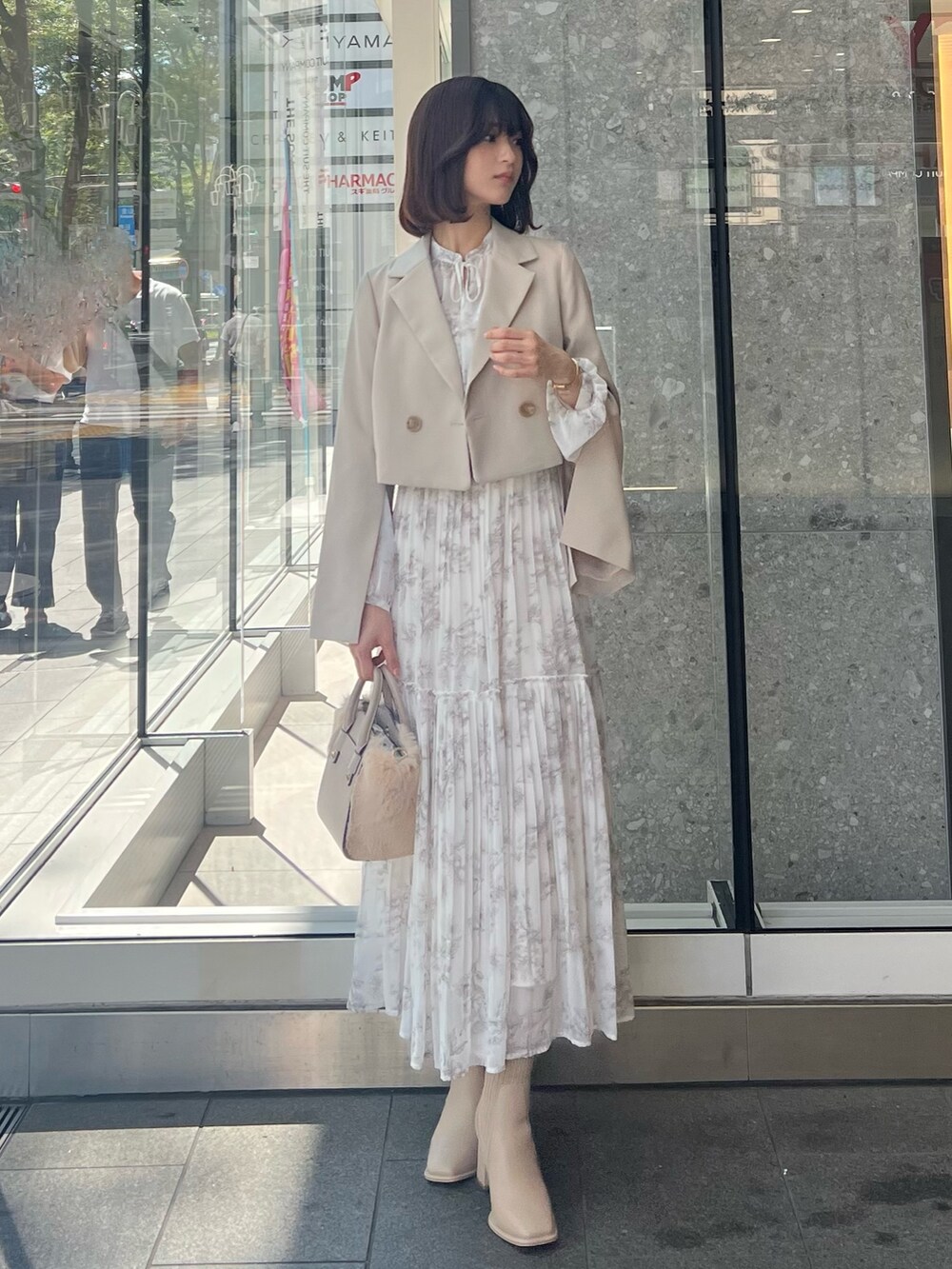 ホワイト系のハンドバッグ、ベージュ系のテーラードジャケット、ベージュ系のブーツを着用したレディースの秋コーディネートの3枚目の写真