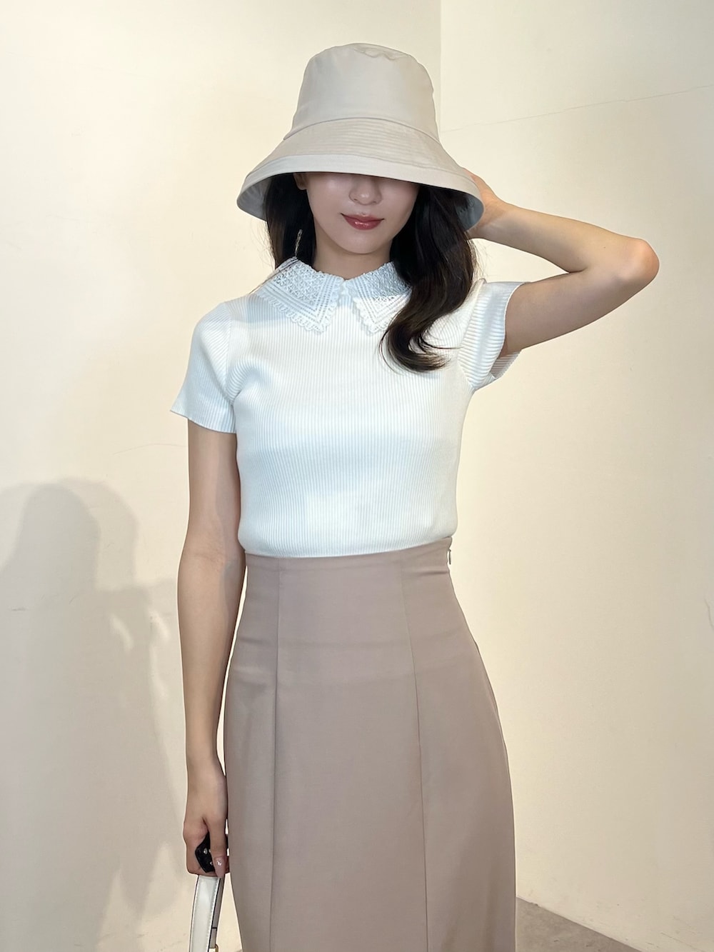 ホワイト系のニット/セーター、ピンク系のスカート、ホワイト系のパンプスを着用したレディースの春コーディネートの2枚目の写真