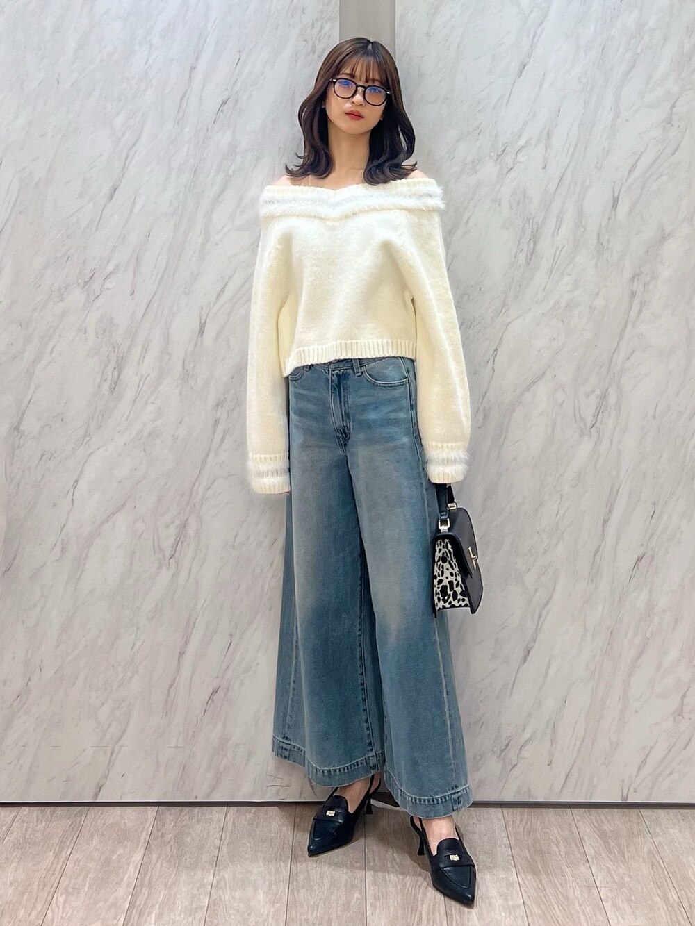 ホワイト系のニット/セーター、ブルー系のデニムパンツ、ブラック系のハンドバッグを着用したレディースの冬コーディネートの3枚目の写真