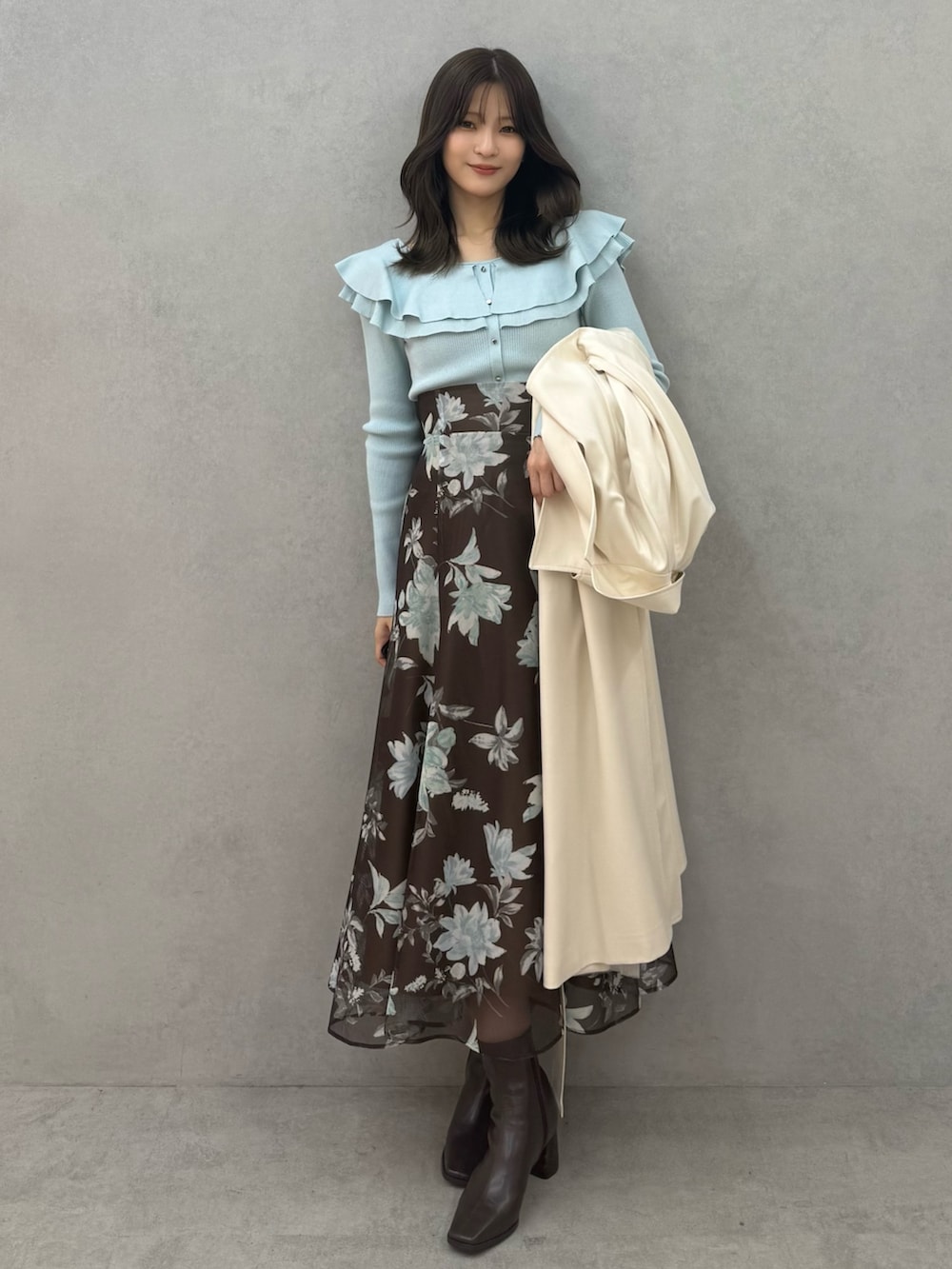 ブラウン系のブーツ、グリーン系のニット/セーター、ブラウン系のスカートを着用したレディースの春コーディネートの3枚目の写真