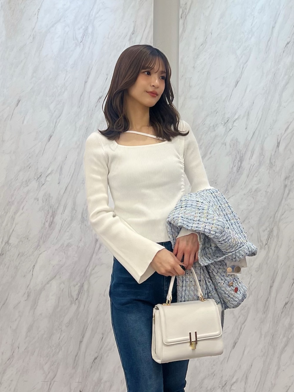 ブルー系のテーラードジャケット、ブルー系のデニムパンツ、ホワイト系のハンドバッグを着用したレディースの冬コーディネートの5枚目の写真