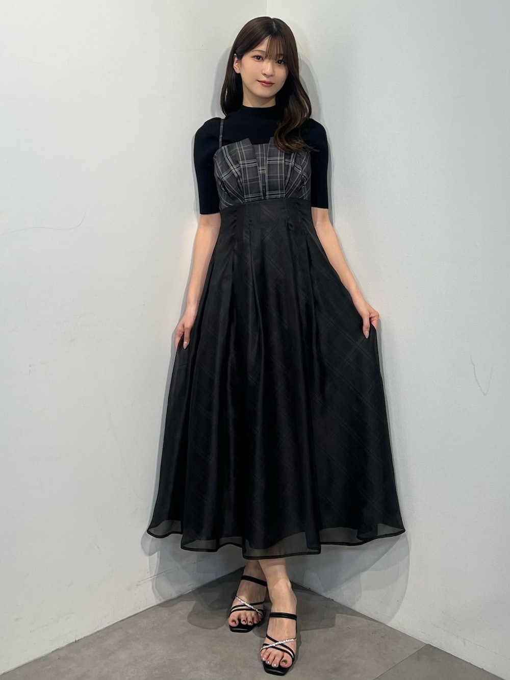 ブラック系のニット/セーター、ブラック系のワンピース、ブラック系のサンダルを着用したレディースの春コーディネートの3枚目の写真